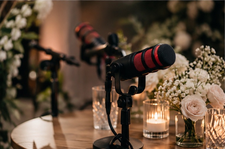 Podcastmicrofoon van dichtbij, met kaarsjes en witte rozen ernaast